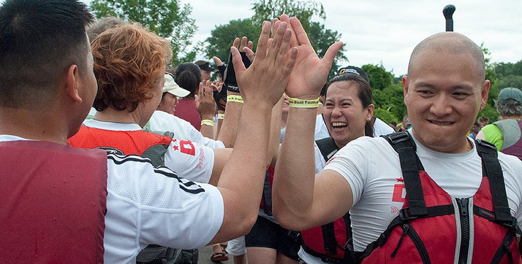 paddlers high fiving each other, smiling, after a race